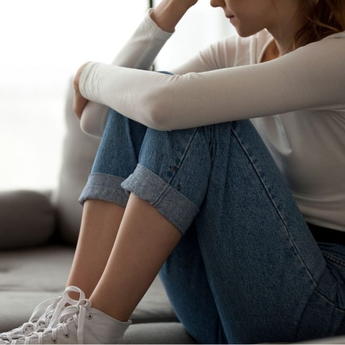 Pessoa observando uma paisagem pela janela, com expressão reflexiva, representando o sentimento de falta e a busca por sentido.